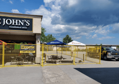 Yellow temporary fence rentals surrounding a Castle John's restaurant to secure their outdoor patio area.