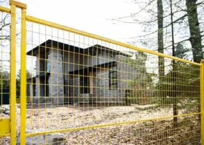 location de clôtures temporaires jaunes installées sur un chantier de construction devant une nouvelle maison
