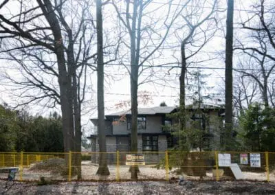 location de clôtures temporaires jaunes installées autour d'un nouveau chantier de construction de maison avec un panneau Modern Fence Rental